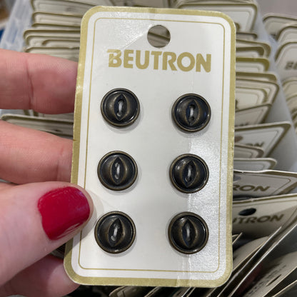 Beutron buttons held by a hand with red nail polish against a background of more buttons.