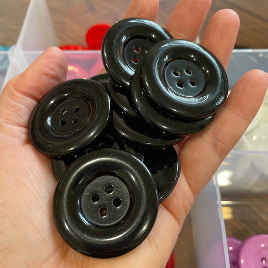 Hand holding four black buttons with a blurred background