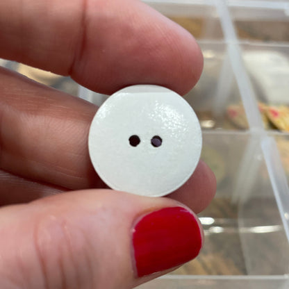White button held between fingers with a blurred background