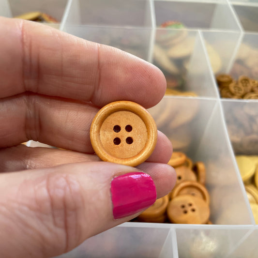 Hand holding a yellow button with a collection of buttons in the background