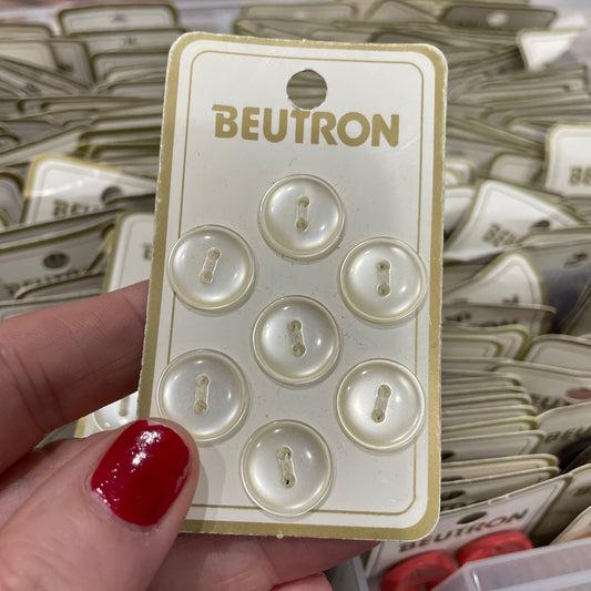 Beutron button packaging held by a hand with red nail polish