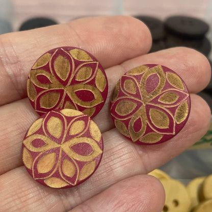 Hand holding decorative buttons with a background of various buttons.