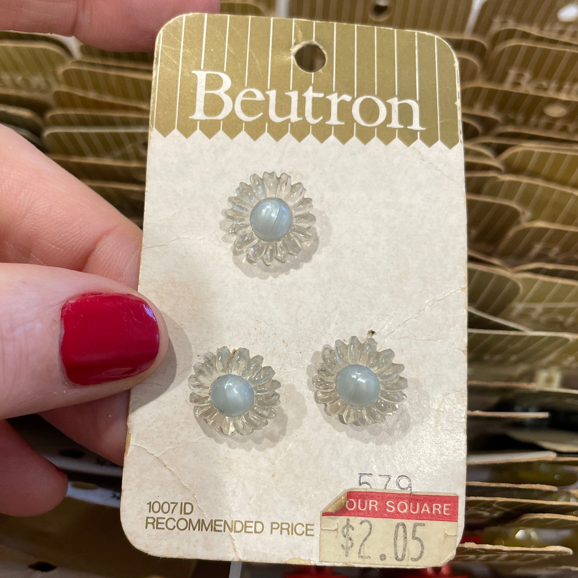 Buttons on a Beutron card held by a hand with red nail polish.