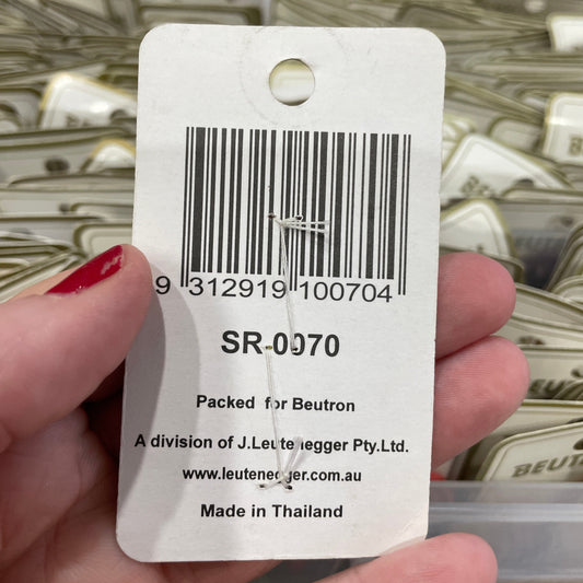 Hand holding a product tag with a barcode and text, with a blurred background of similar products.