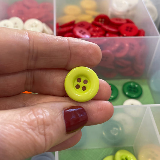 Hand holding a yellow button with a background of button containers.