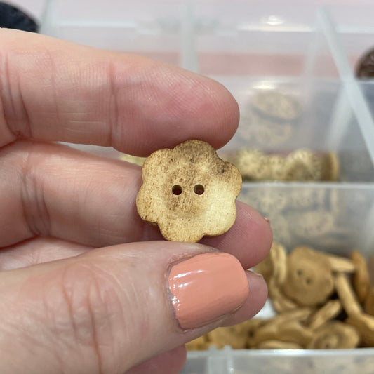 Hand holding a gold button with a collection of buttons in the background