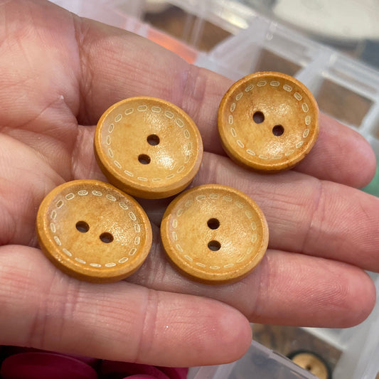 Hand holding yellow buttons with a container of buttons in the background