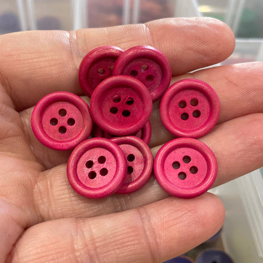 Hand holding pink buttons with a blurred background