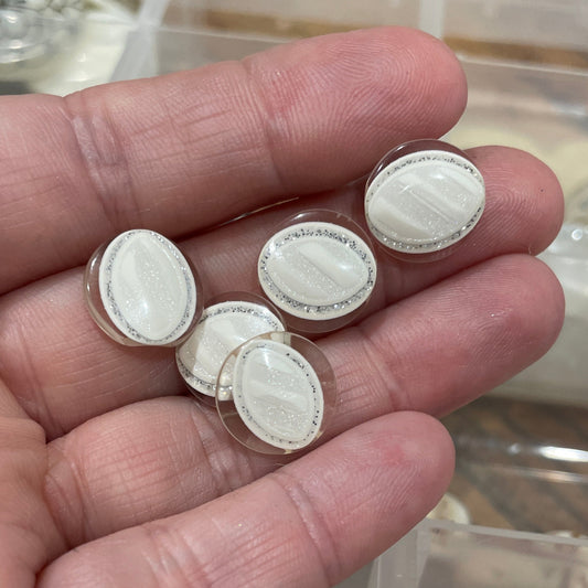 Hand holding white oval stones with a background of red stones in a container