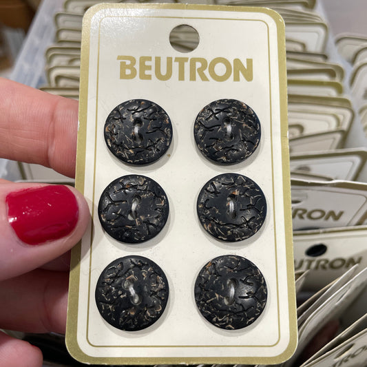 Beutron buttons on a card held by a hand with red nail polish.