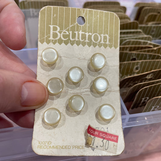 Hand holding a buttons with a clear container in the background.