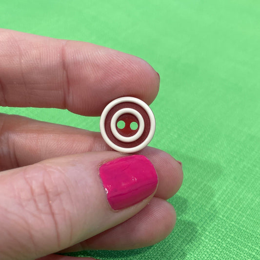 Hand holding a small circular object with a green fabric background