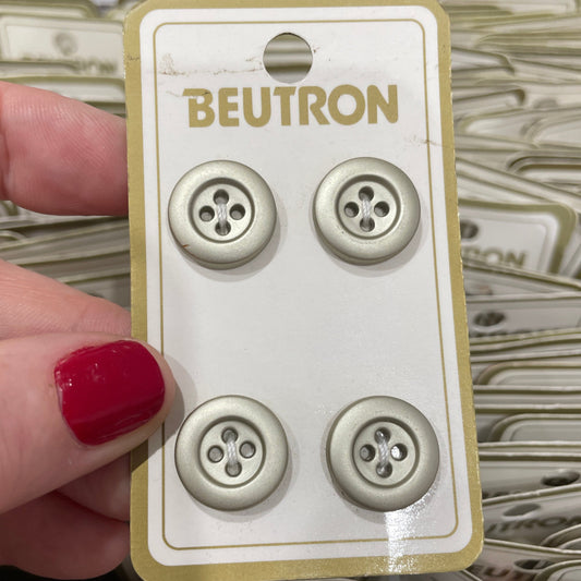 Card with three buttons held by a hand with red nail polish, with 'Beutron' branding.