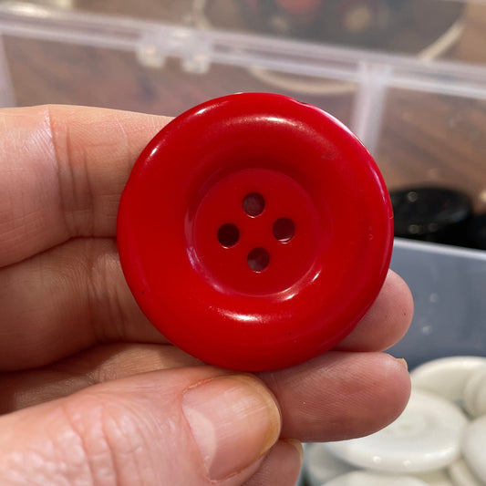 Red button held in a hand with a blurred background