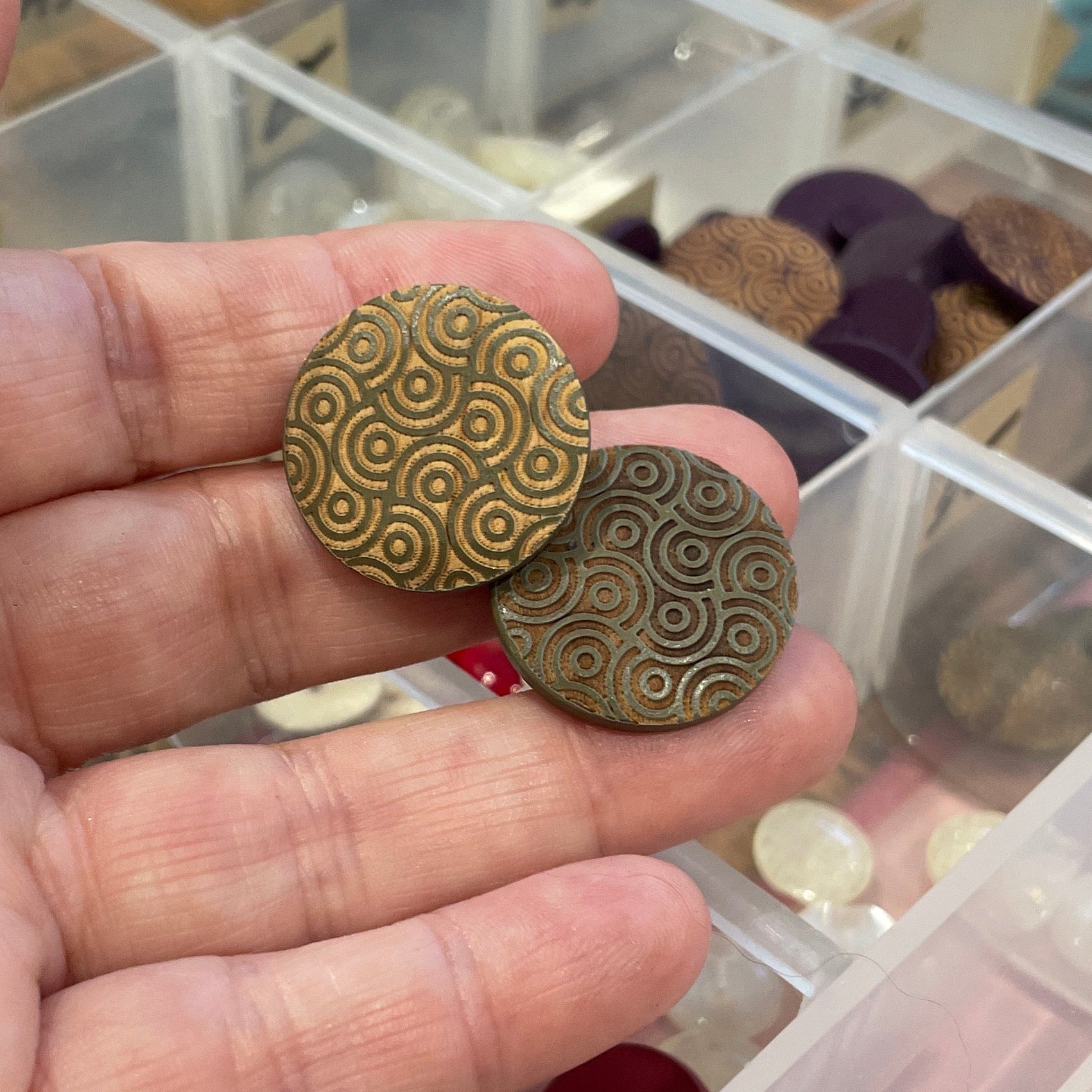 Hand holding buttons with a clear container of buttons in the background
