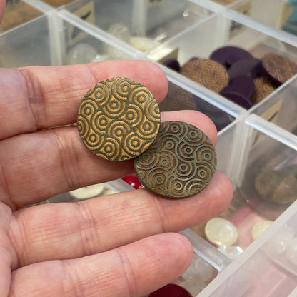 Hand holding buttons with a clear container of buttons in the background