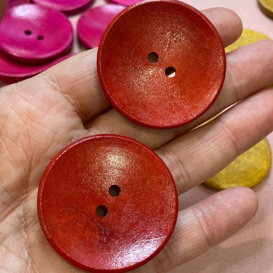 Hand holding two red buttons with a background of colorful buttons