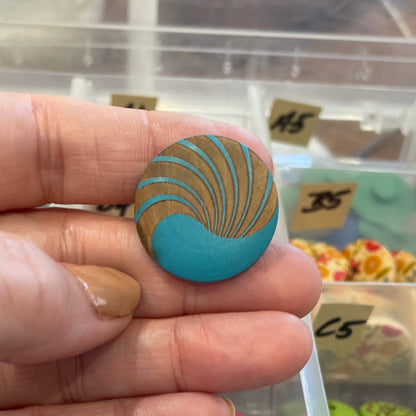 Hand holding a blue and gold decorative item with a display of similar items in the background.