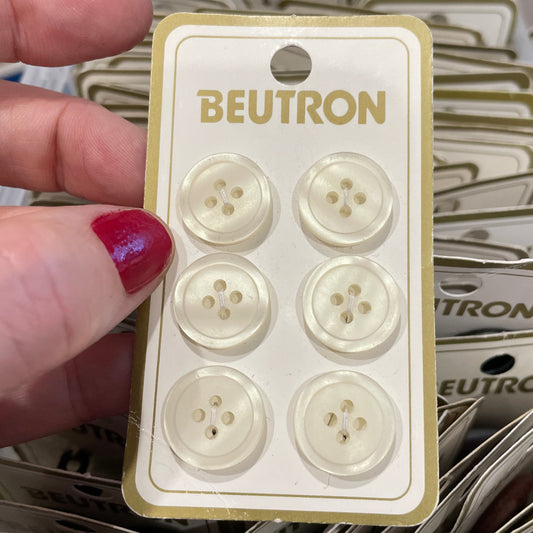 Beutron buttons on a card held by a hand with red nail polish, surrounded by more button cards.