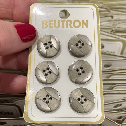 Packaging of metallic buttons with 'Beutron' branding held by a hand.