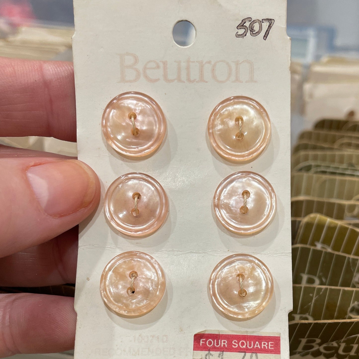 Set of pearl buttons on a plastic card held by a hand with a blurred background