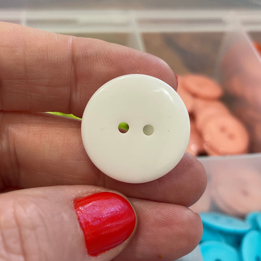 Hand holding a white button with colorful buttons in the background
