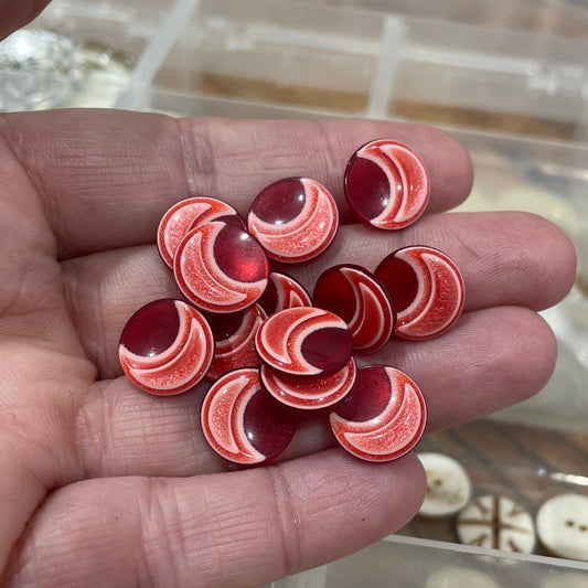 Hand holding red and white circular objects with a blurred background of similar items.