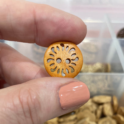 Hand holding a decorative button with a background of button assortment