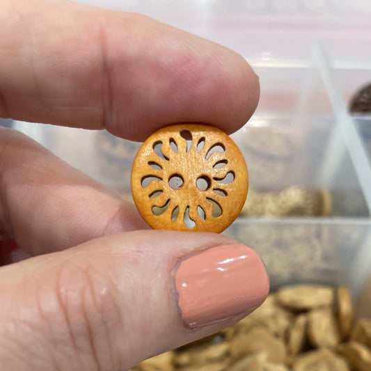 Hand holding a decorative button with a background of button assortment