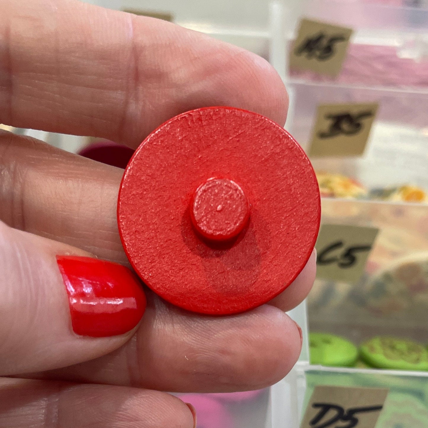 Hand holding a red button with button collection in the background