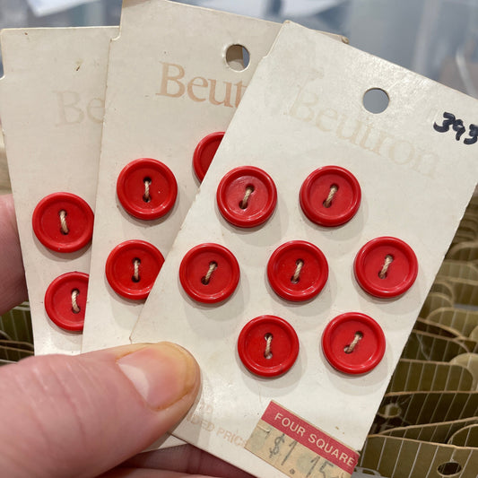 Red buttons on a cardboard template held by a hand with a blurred background