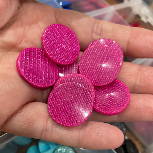 Hand holding pink buttons with a container of various buttons in the background