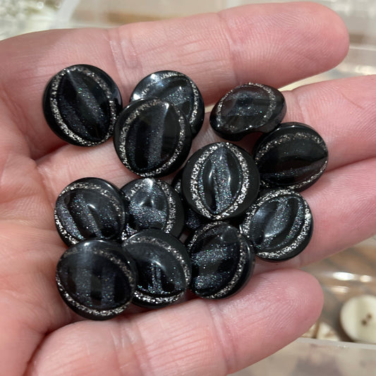 Hand holding black oval-shaped objects with a background of various buttons.