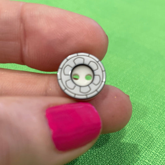 Small round object held between fingers against a green background
