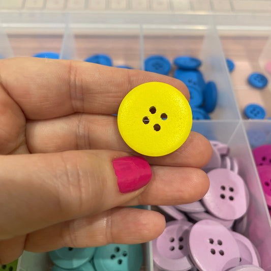 Hand holding a yellow button with a collection of colorful buttons in the background