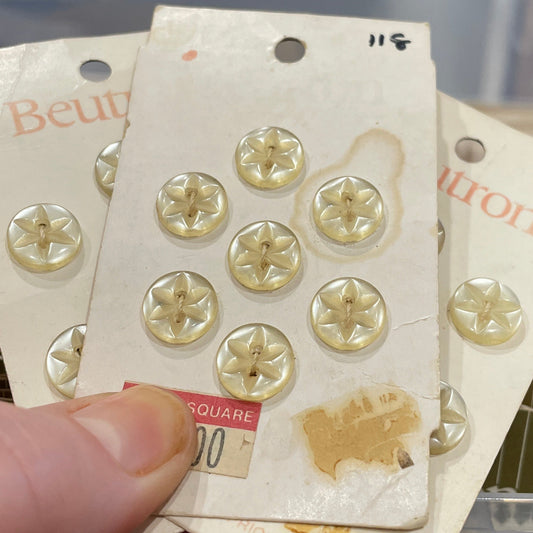 Gold buttons on a card held by a hand with a blurred background