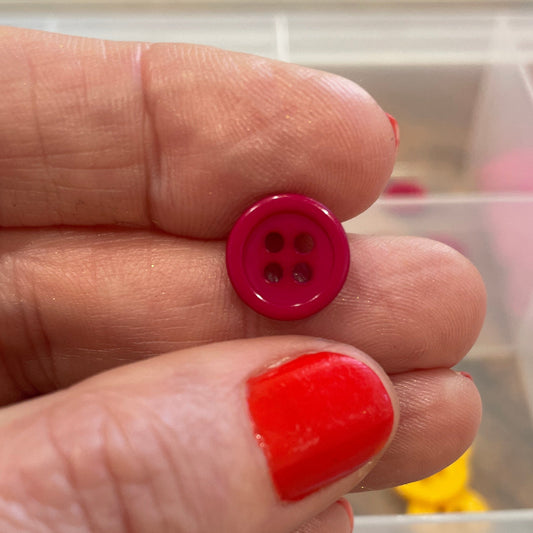 Hand holding a red button with colorful buttons in the background