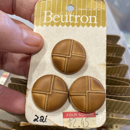 Packaged leather look buttons held by a hand with a blurred background