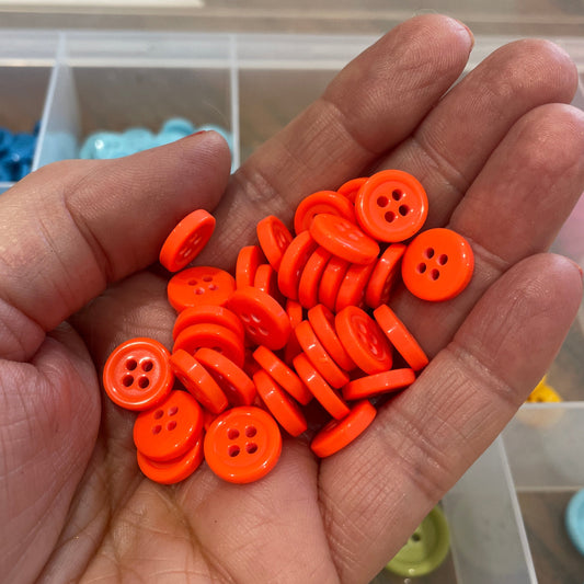 Hand holding a small pile of orange buttons with a blurred background