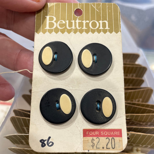 Card with black and beige buttons held by a hand, with a blurred background