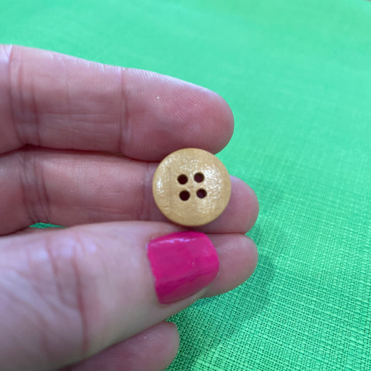 Small yellow button held between fingers against a green background