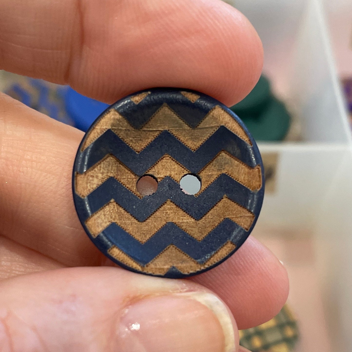 Hand holding a button with a zigzag pattern against a background of various buttons.