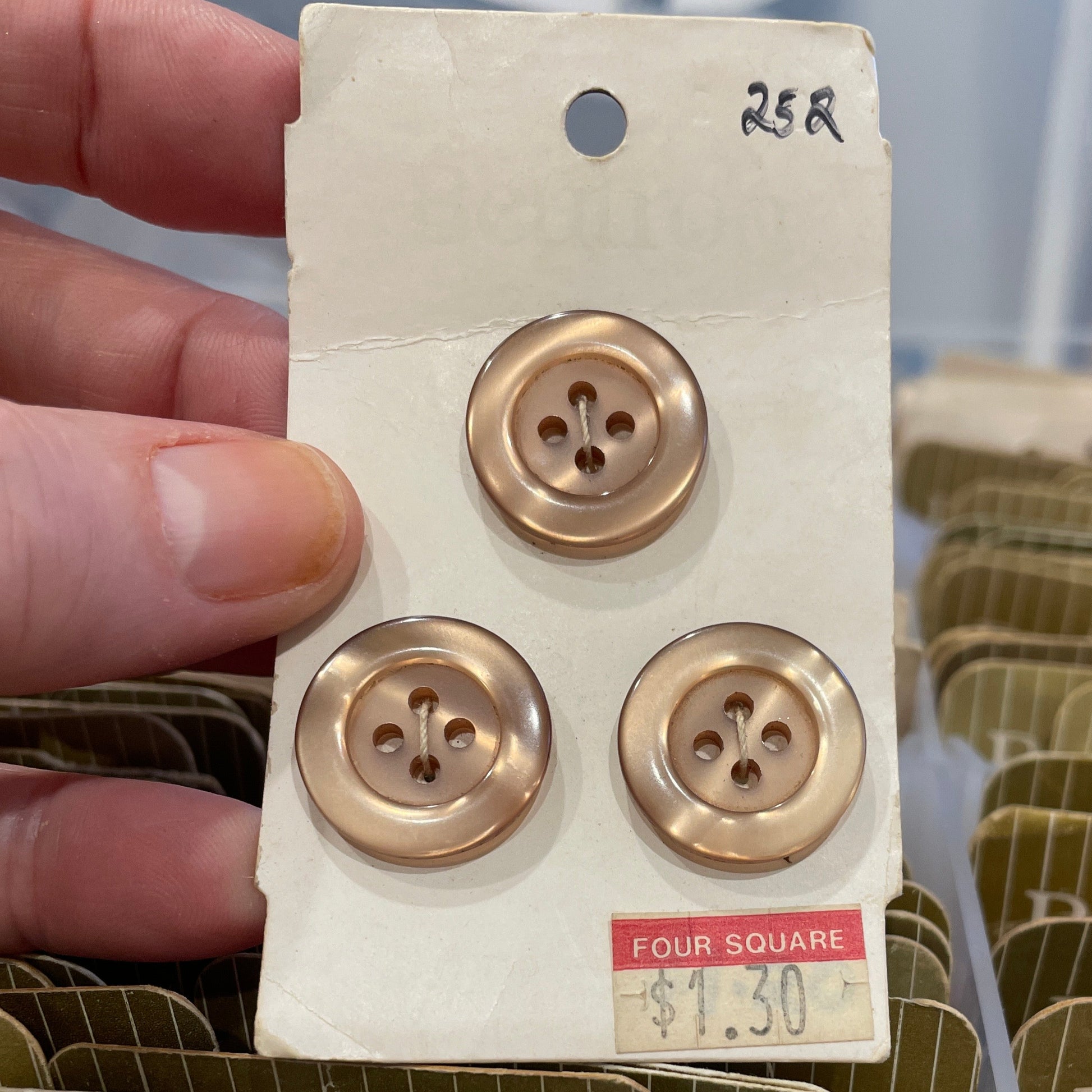 Three gold buttons on a card held by a hand with a blurred background