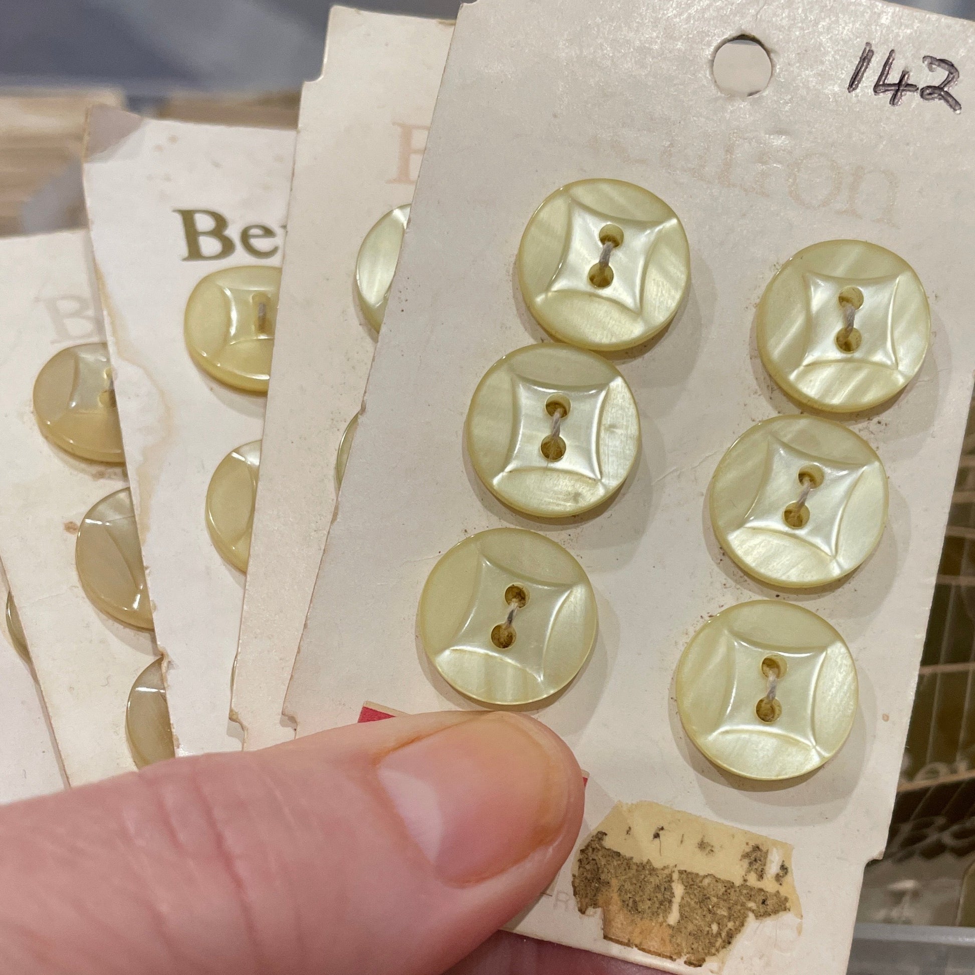 Hand holding a card with gold buttons against a blurred background