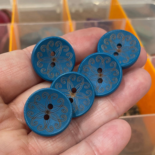 Hand holding blue buttons with a blurred background of a button organizer.