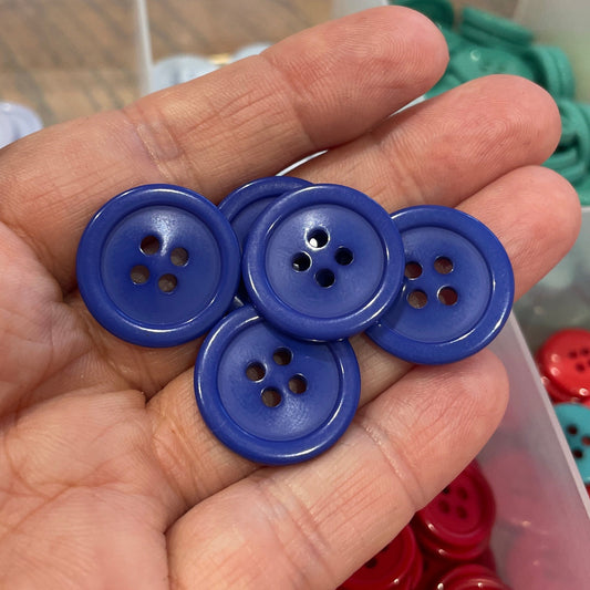 Hand holding blue buttons with a container of red and blue buttons in the background