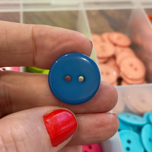Hand holding a blue button with colorful buttons in the background