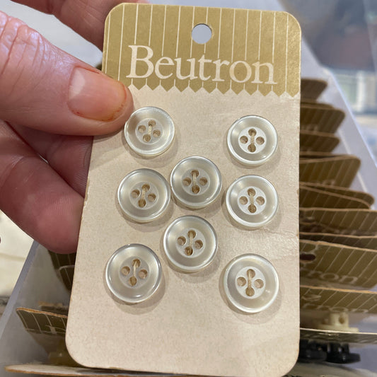 Hand holding a card with buttons labeled 'Beutron' in a store setting.