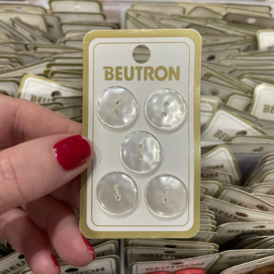Packaged buttons with 'Beutron' branding held by a hand.