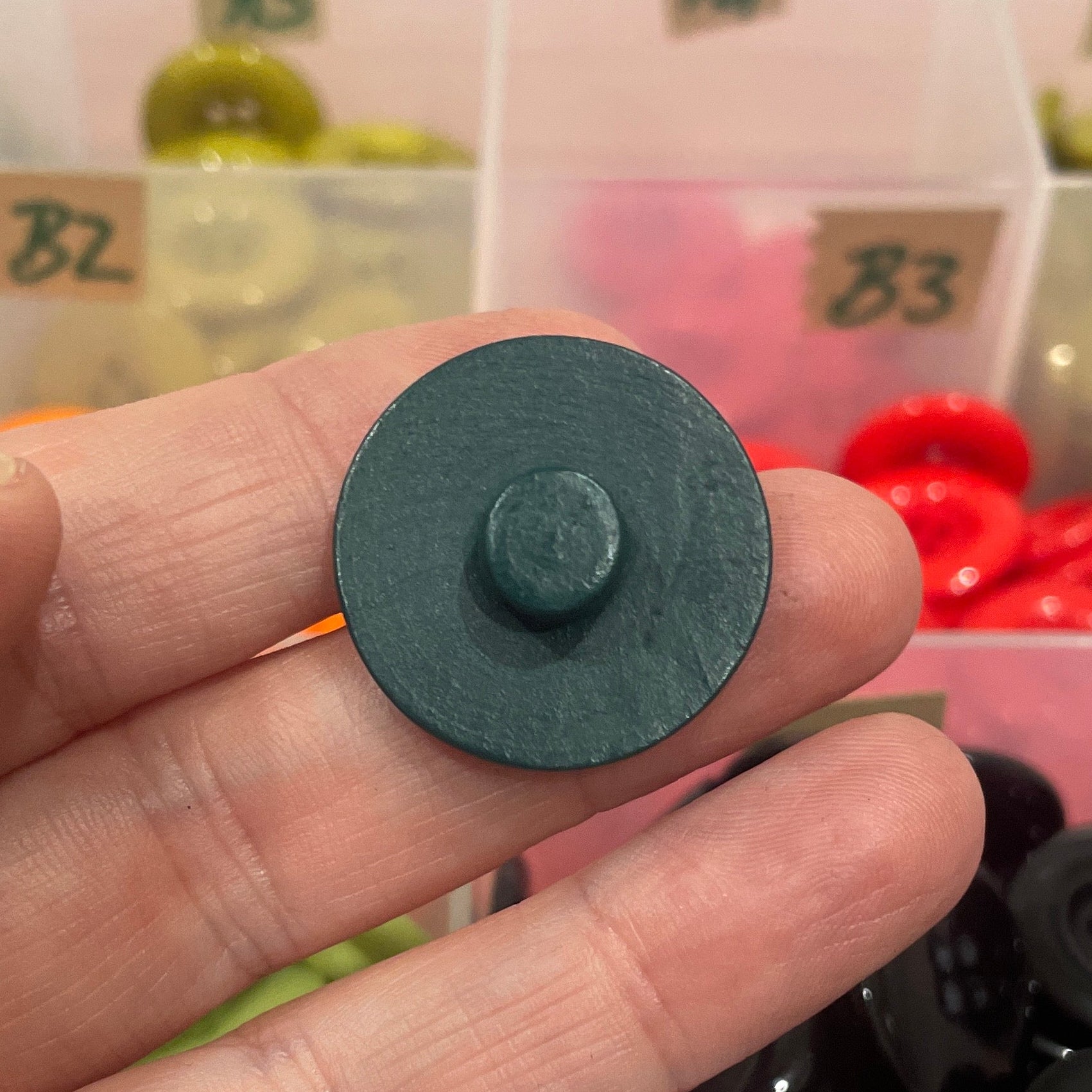 Person holding a button with a container of buttons in the background